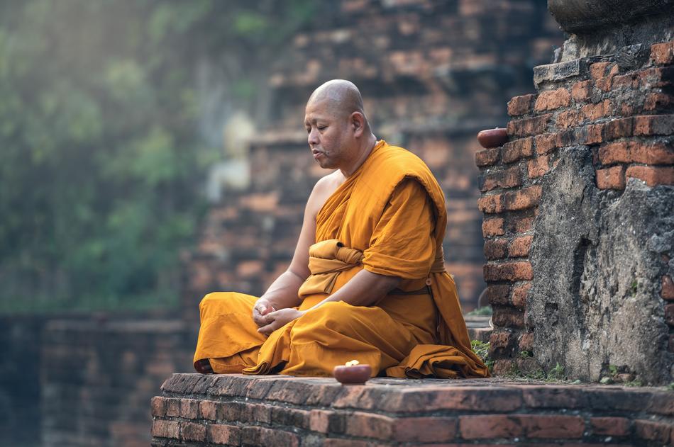 Buddhist monk sits on a ruined brick building in Burma