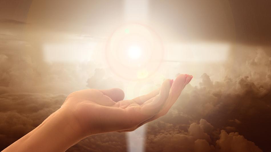 hand on the background of a bright cross with the light