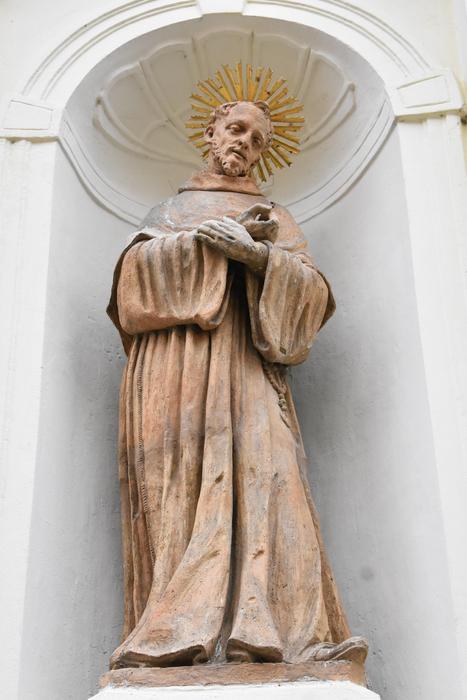 Beautiful, gold statue, on the white wall, with the arch