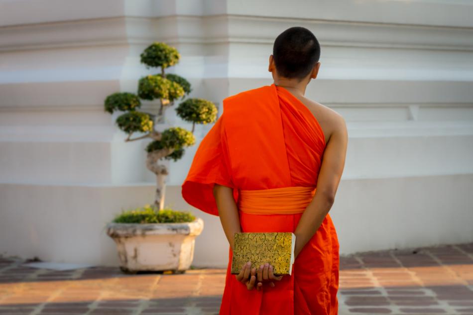 Buddhist monk looks at the facade of a monastery in Bangkok
