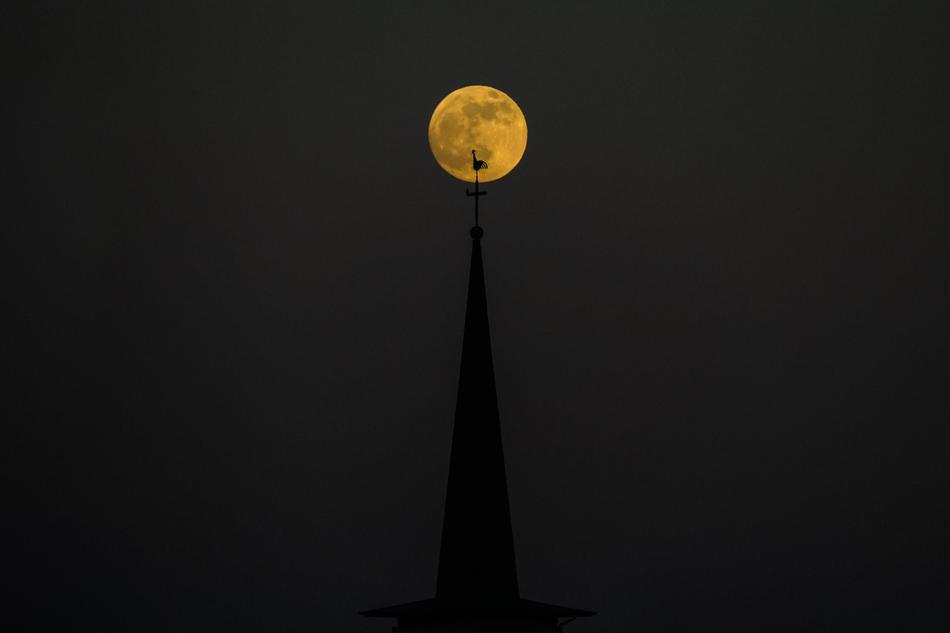 spire of a cathedral in Luxembourg on a background of a full yellow moon