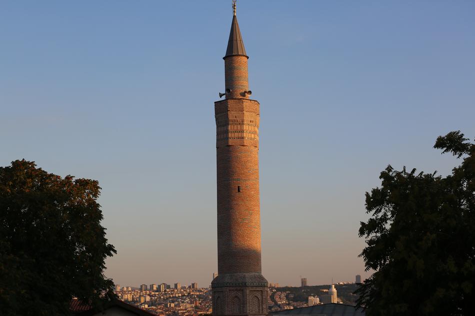 tall brick Minaret in front of city at dusk in turkey, istanbul