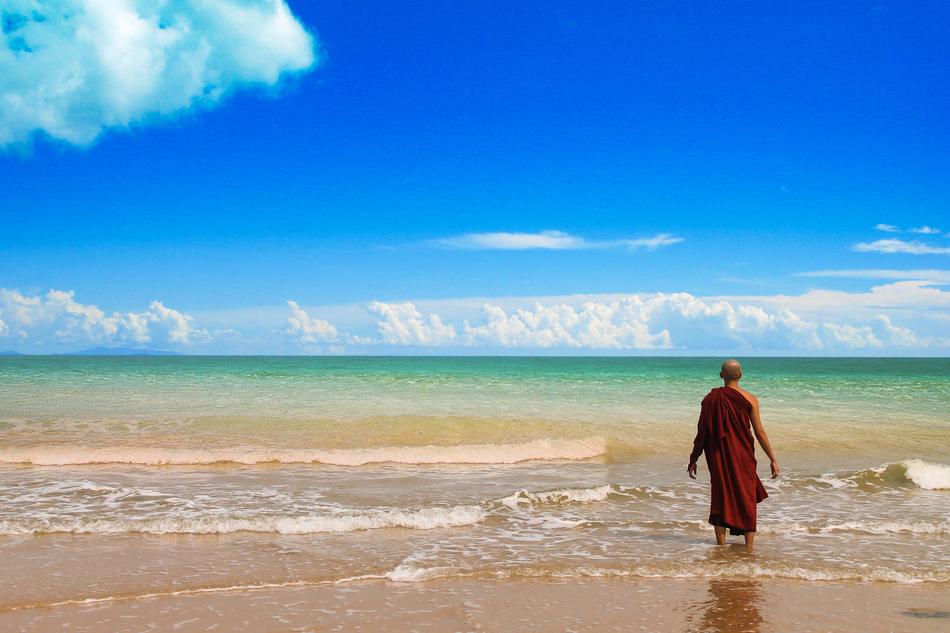 Monk of Theravada Buddhism, on the beautiful, sandy beach with green water
