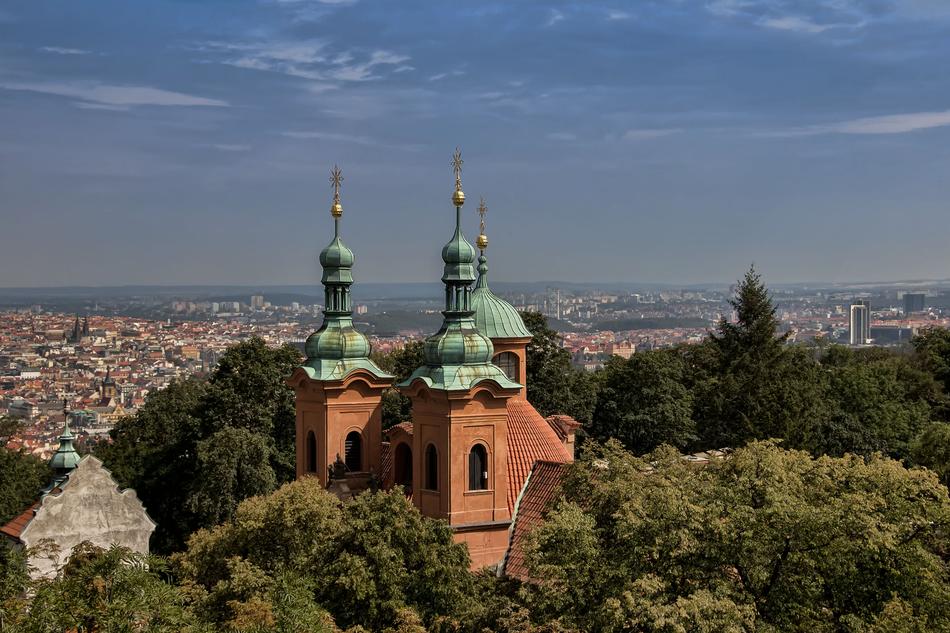 towers of Baptist Cathedral of st lawrence at panoramic view among green plants of city, Czech, Prague