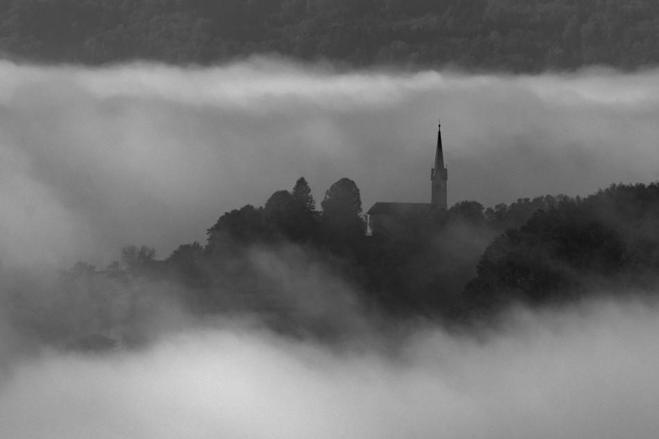 black and white panoramic photo of a church in the fog in Dolenjska, Slovenia