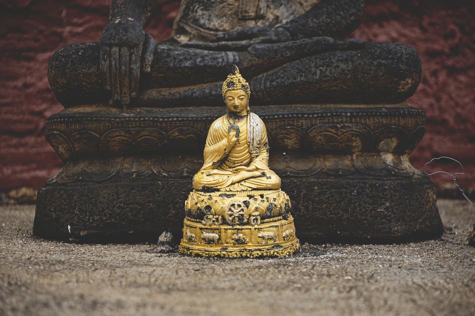 golden buddha statue on the background of a stone statue