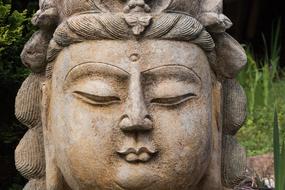 Beautiful sculpture of Buddha, near the green plants, in Guanyin, China