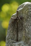 Beautiful Jesus cross on the stone at blurred background with green and yellow plants