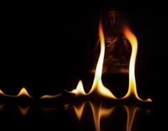 Colorful flame near the beautiful Buddha statue, among the darkness