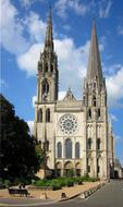 Beautiful Chartres Cathedral with the green trees, under the blue sky with clouds, in France