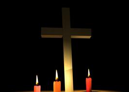 white cross and burning red candles