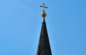 Beautiful spire steeple with the cross, at blue sky background