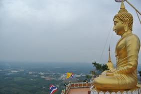 Beautiful, shiny, gold Buddha statue in the Tiger Cave Temple, on the landscape in Krabi, Thailand