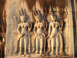 sculptures of women on the wall of a temple in cambodia