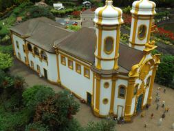Beautiful miniature model of the golden and white church among the green trees in Brazil