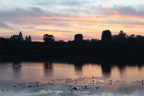 silhouette of the temple and trees near the river in the morning