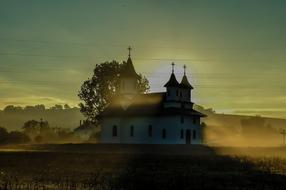 Beautiful and colorful, foggy landscape with the church, among the plants, at colorful and beautiful sunrise