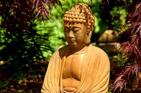 Buddha statue near Japanese Maple tree in Garden