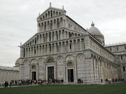 People, near the beautiful cathedral, under the cloudy sky, in Lucca, Tuscany, Italy