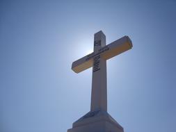 cross in the rays of the bright sun against the background of the sky