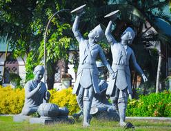 Statue of the people, among the colorful and beautiful plants, near the colorful architecture