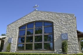 Beautiful chapel with the cross and window, with the green garden, under the blue sky