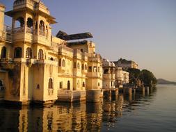 Beautiful temple, on the shore of the lake with reflection, in India, at colorful sunset