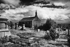 Black and white photo of the beautiful Friarmere church, among the plants, in Delph, England