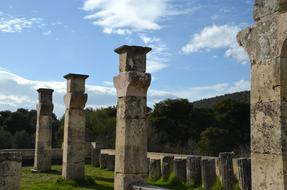 Beautiful antique pillars among the green plants in Peleponnes, Greece