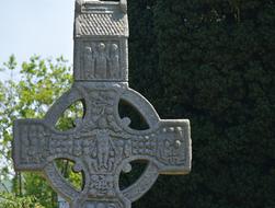 Beautiful, patterned, gray cross, near the green plants, in Ireland