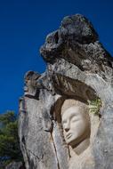 Beautiful and colorful sculpture with the faces, at beautiful blue sky on background