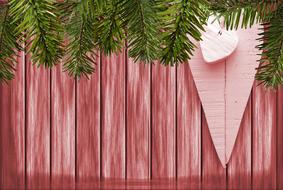 Beautiful, wooden, red Christmas wall with the green fir branches and pink hearts