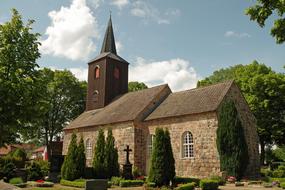 Beautiful church, with the cross, among the green plants, under the blue sky with white clouds