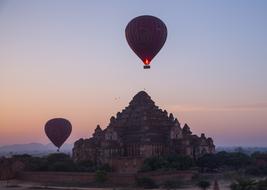 balloons fly over temples at dusk