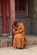 Person, sitting on the chair, near the red columns of the temple