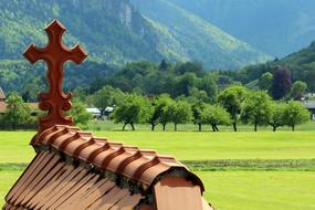 Beautiful roof bridge with the cross, among the green fields, mountains and trees