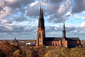Beautiful church, among the colorful trees in Uppsala, under the cloudy sky, in Sweden