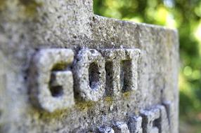 "God" sign on the old, stone statue, near the green plants