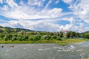 green trees and a church by the river