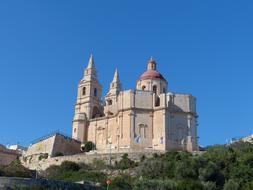 Beautiful church, among the green plants, at blue sky on background, in Melieha, Malta