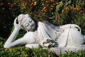 Beautiful Buddha statue, among the colorful plants, in sunlight