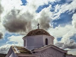 Beautiful dome of the church with cross, at blue sky with white clouds on background, on Skopelos, Greece