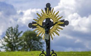 cross with crucifix and golden sun on blurred background