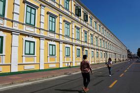 People on the road, near the beautiful yellow and white building in Bangkok, Thailand