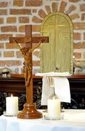 Beautiful wooden cross with Jesus among the white candles, in the church