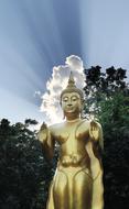 golden Buddha statue on a background of white clouds and blue sky