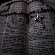 silver cross with chain over open holy Book