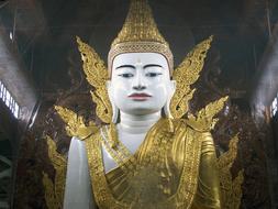 Beautiful, shiny, white and gold Buddha statue with decorations, in the temple