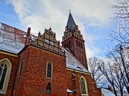 Beautiful and colorful church with the steeple, in snow, among the trees