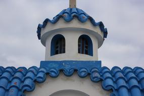 Beautiful church with blue tiles, in Greece, under the clouds